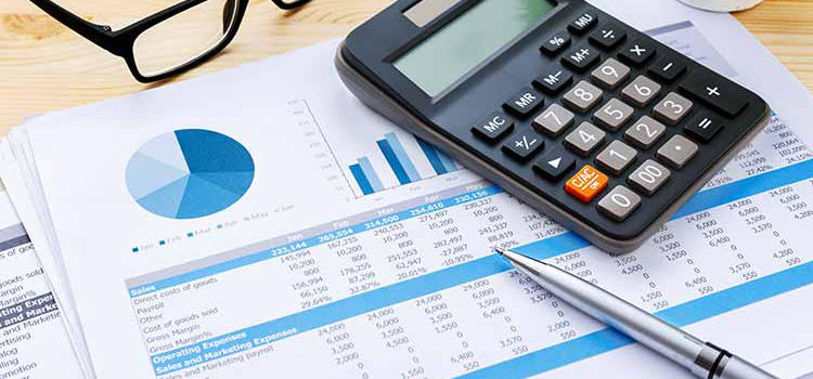 Desk Covered in Charts, Calculator and Reading Glasses